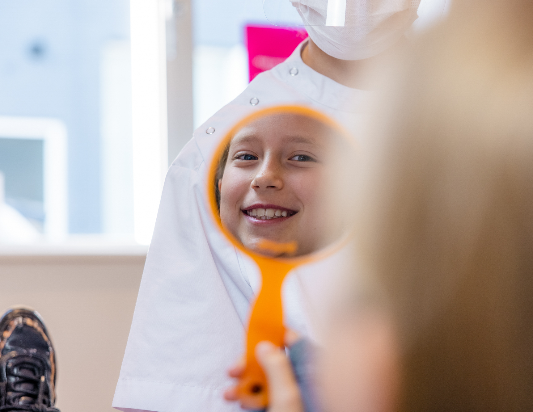 Mondhygiënist laat kind zijn tanden zien in de spiegel