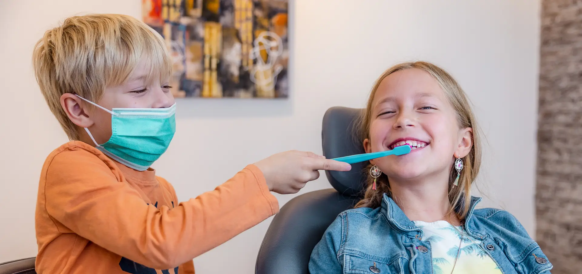 Twee kinderen zitten samen in de behandelstoel bij de mondhygiënist